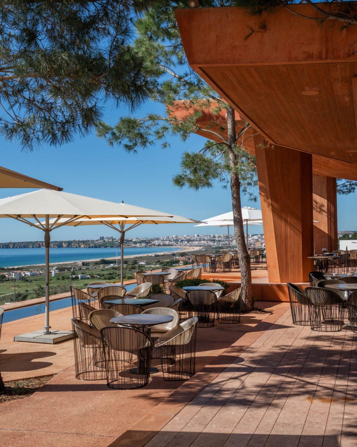 Clubhouse terrace tables under pines with views over Lagos Bay
