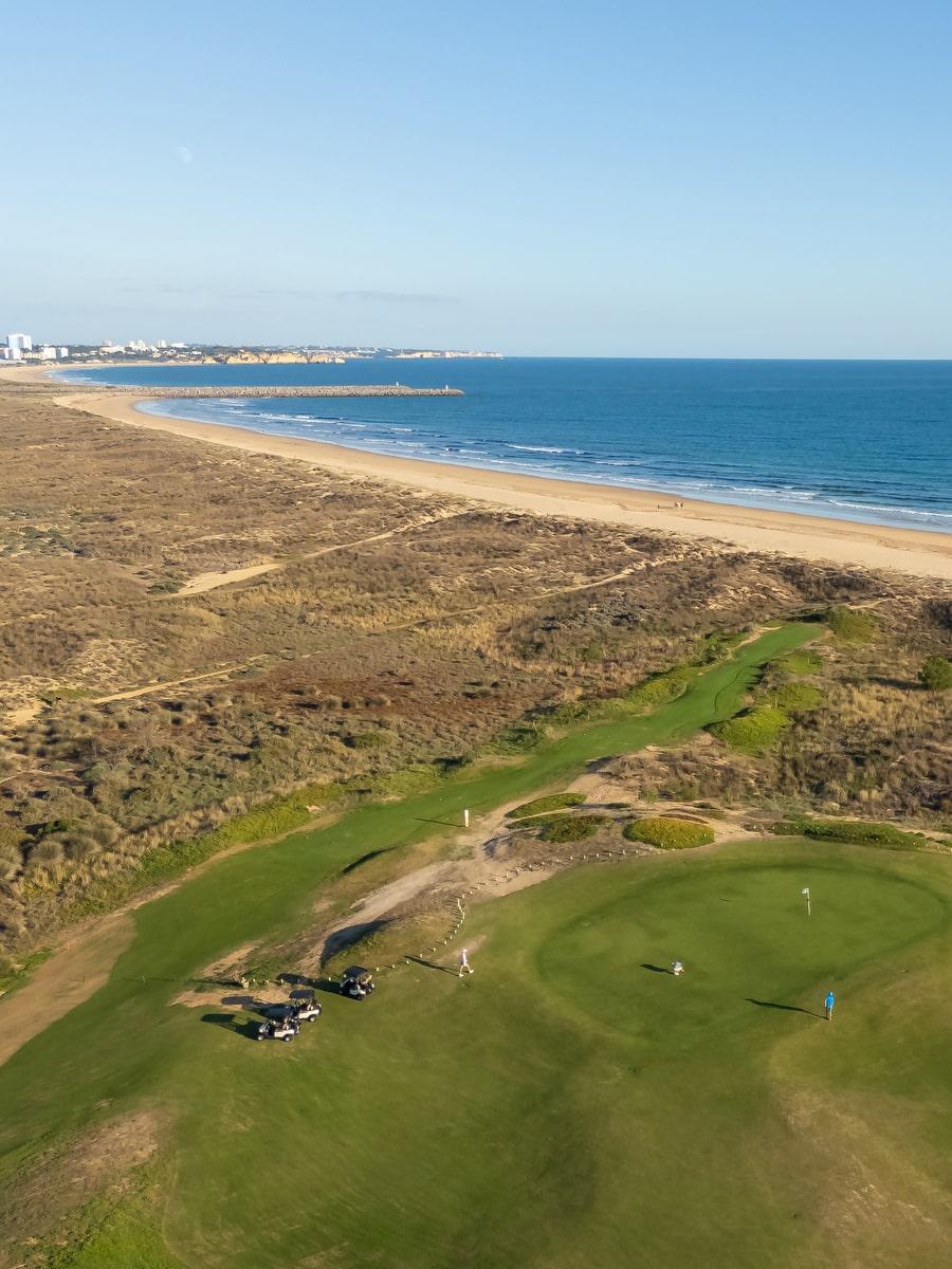Aerial view of a green and fairway among coastal dunes beside the beach at Palmares