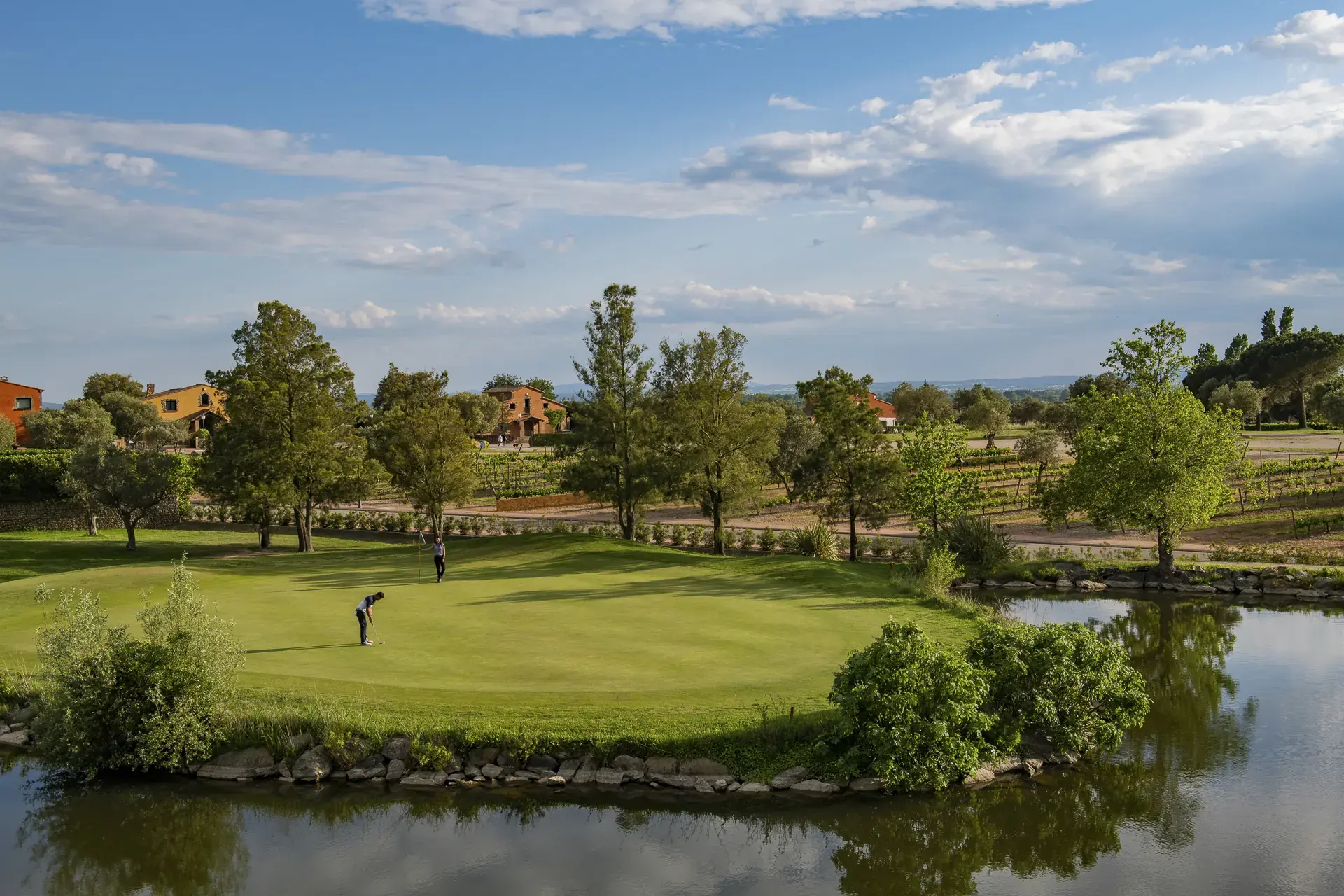 Golfers putting on a waterside green at Golf Peralada