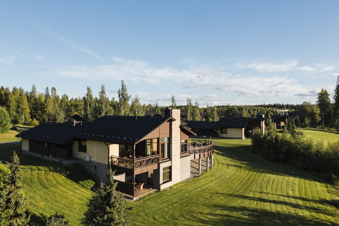 Timber cottage with a terrace and chimney on a grassy hillside