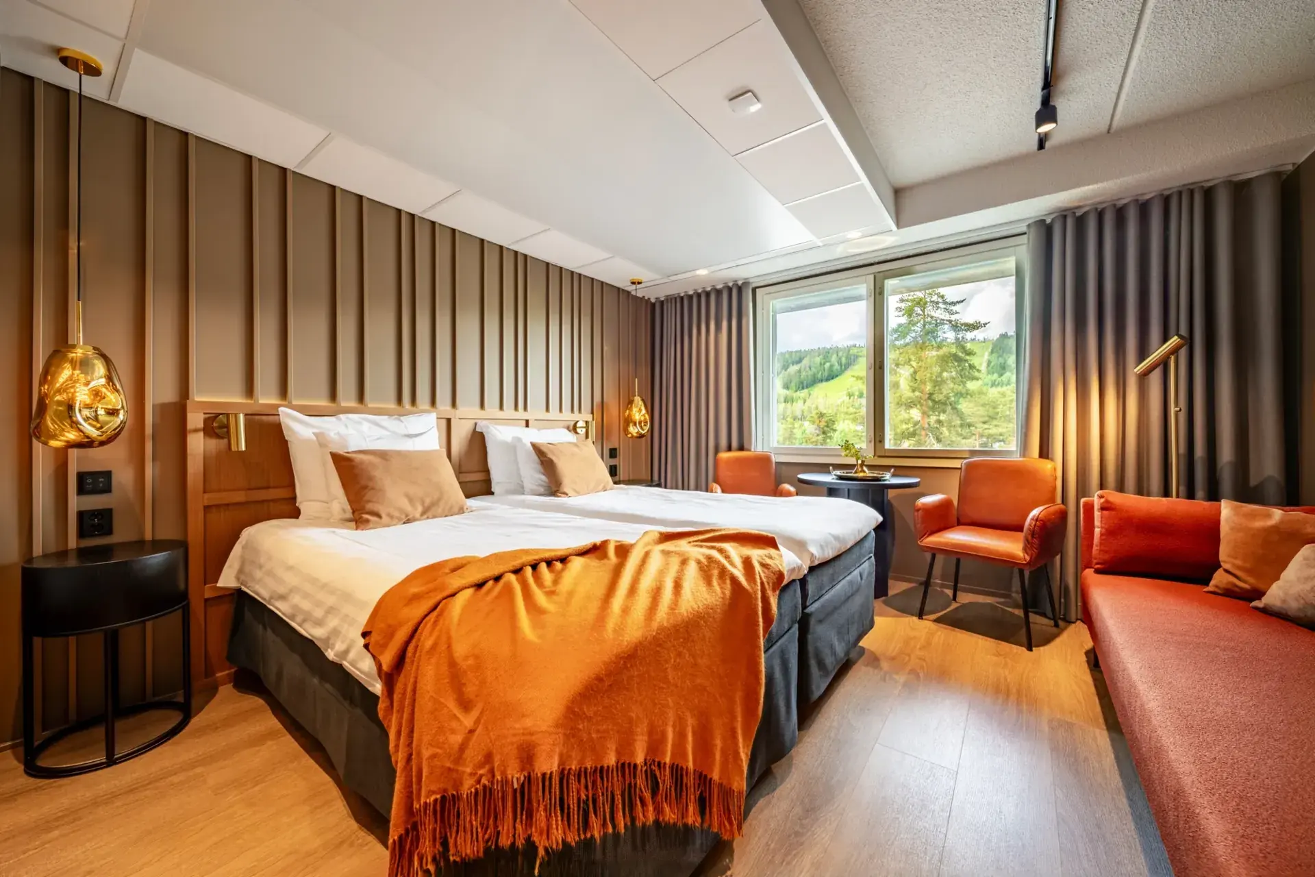 Twin hotel room with a window onto the wooded fell and ski slope