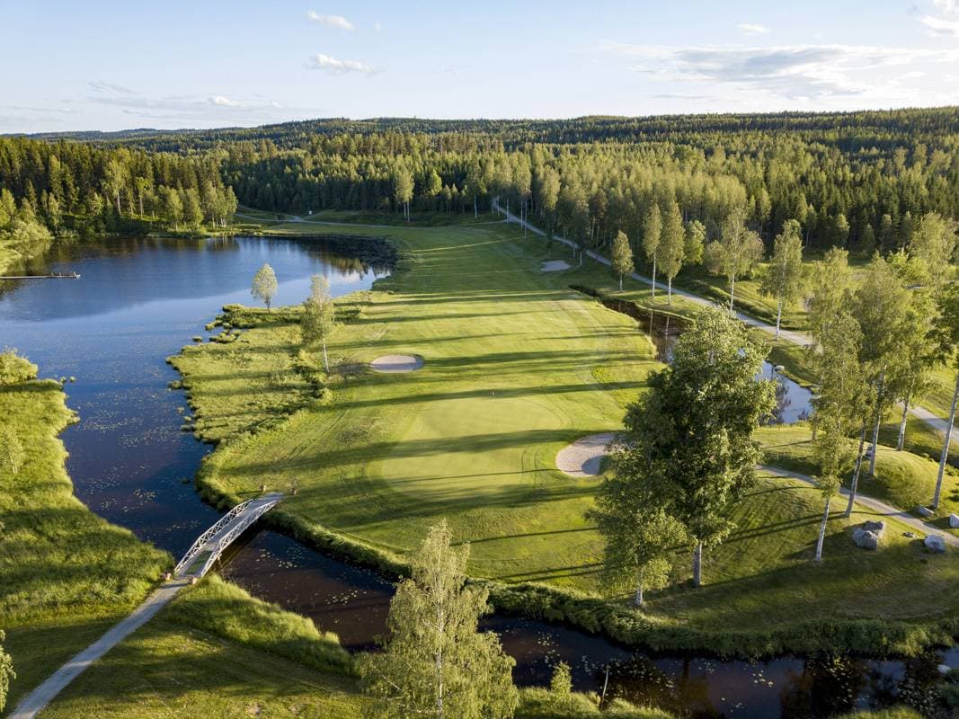 Aerial view of a fairway beside a lake and footbridge on Tahko Golf's Lake & Forest course