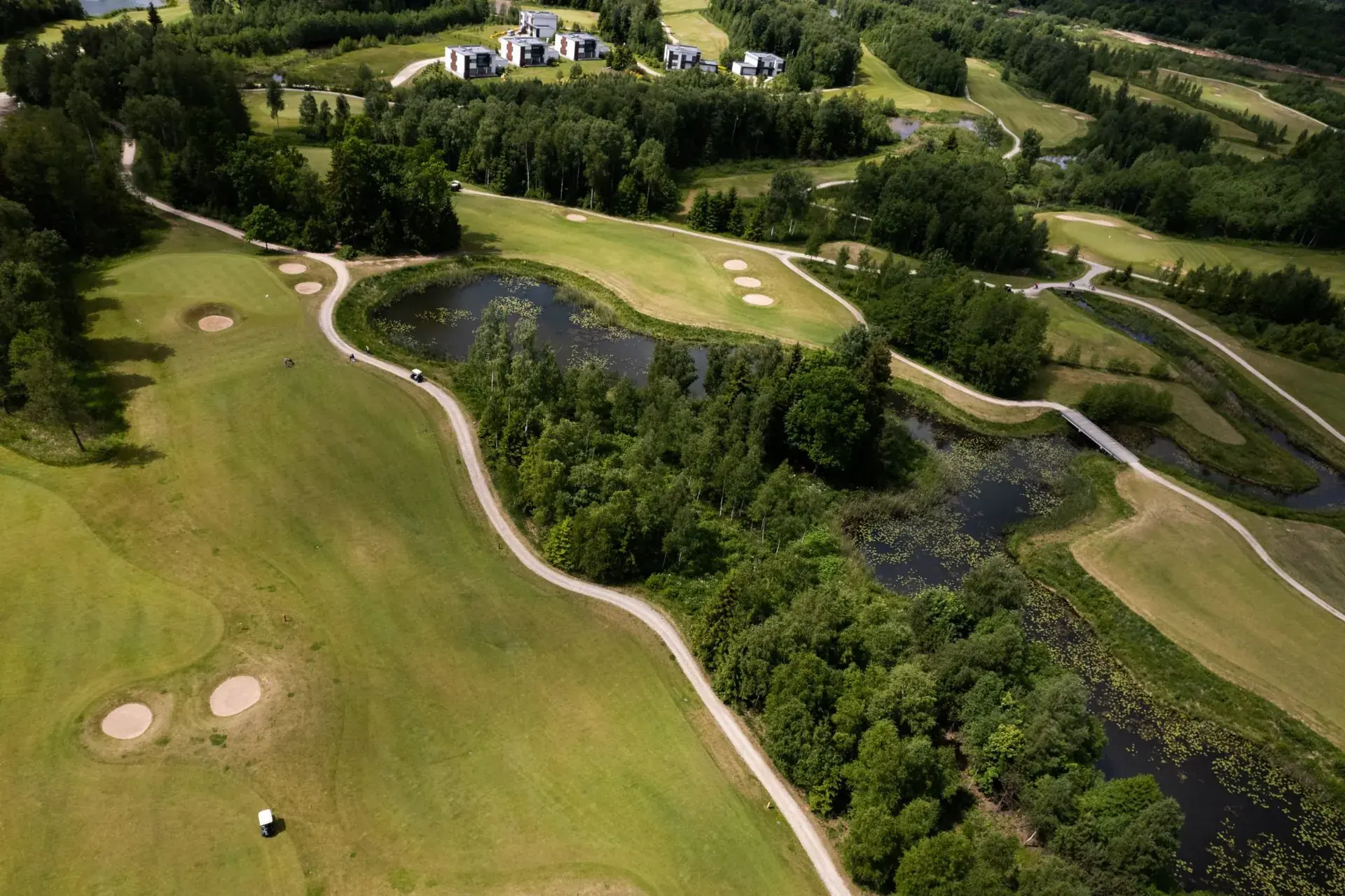 Aerial view of a fairway, bunkers and ponds with villas in the distance at The V Golf Club